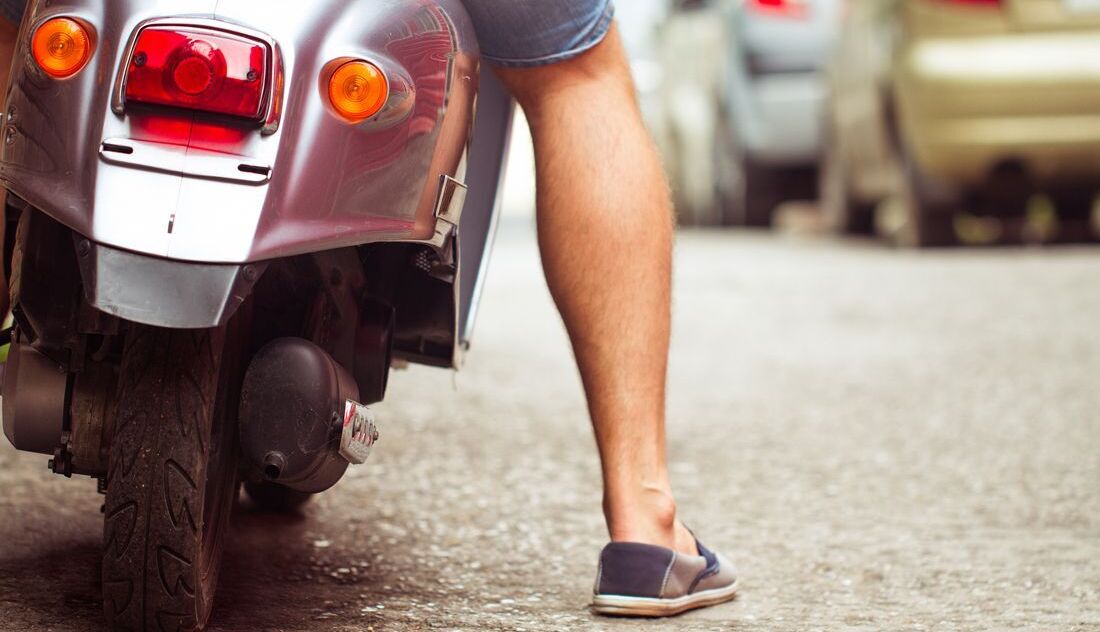 Mann auf Motorroller mit Fuß auf dem Boden
